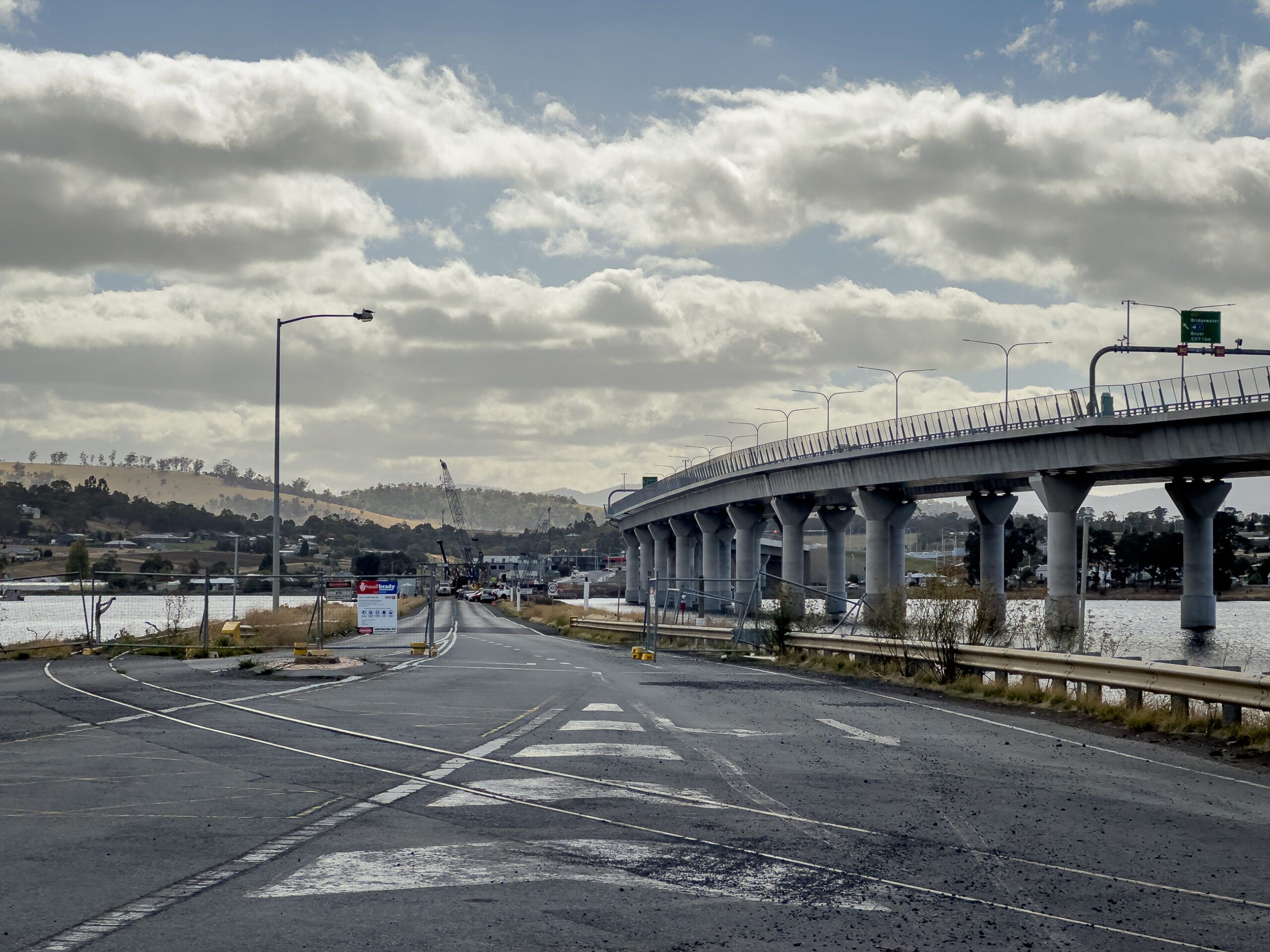 A wide view of a bridge. In the background the previous bridge is in the last stages of being dismantled