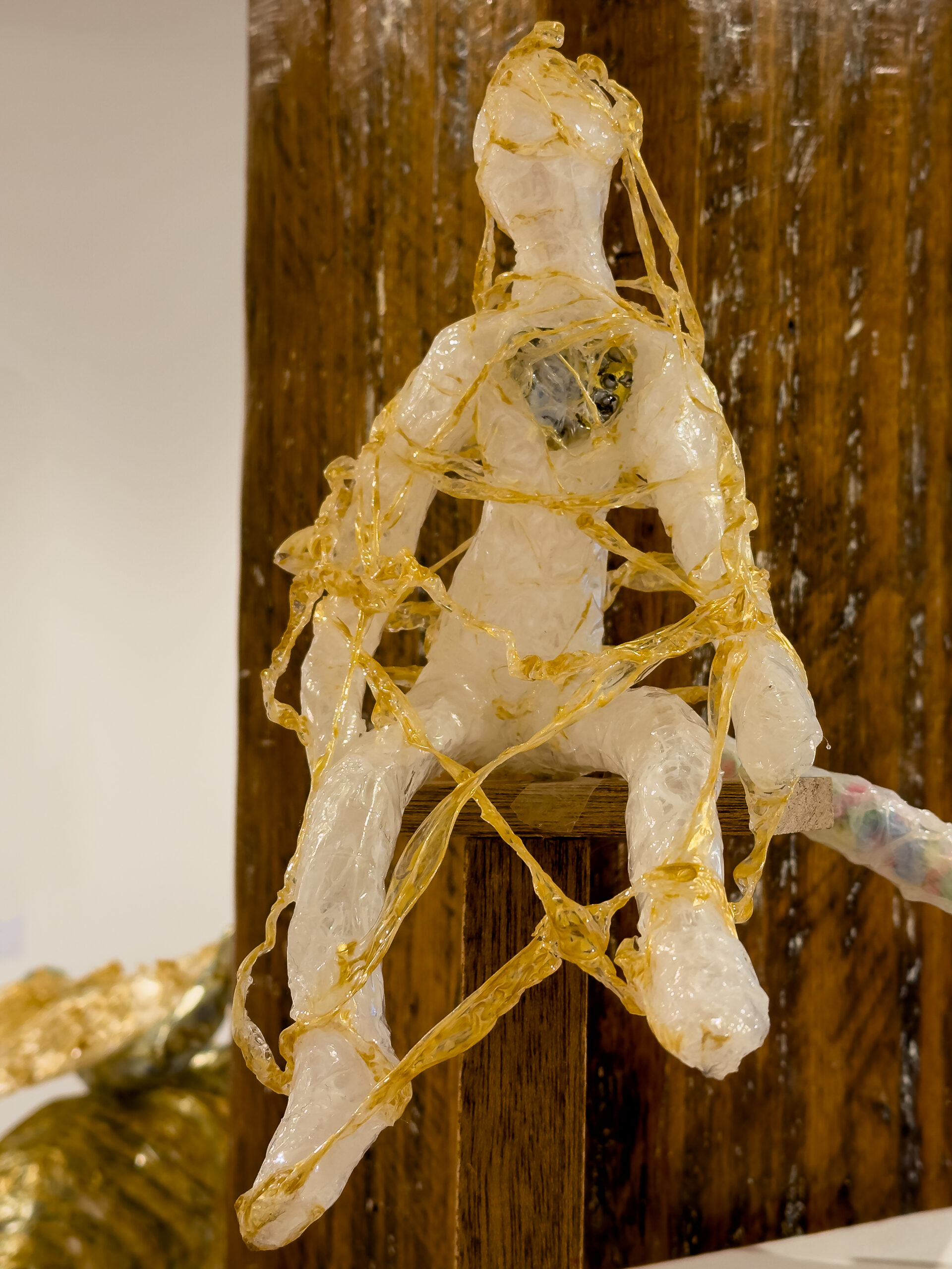 A sculpture of a person made from sticky tape covered in golden strings