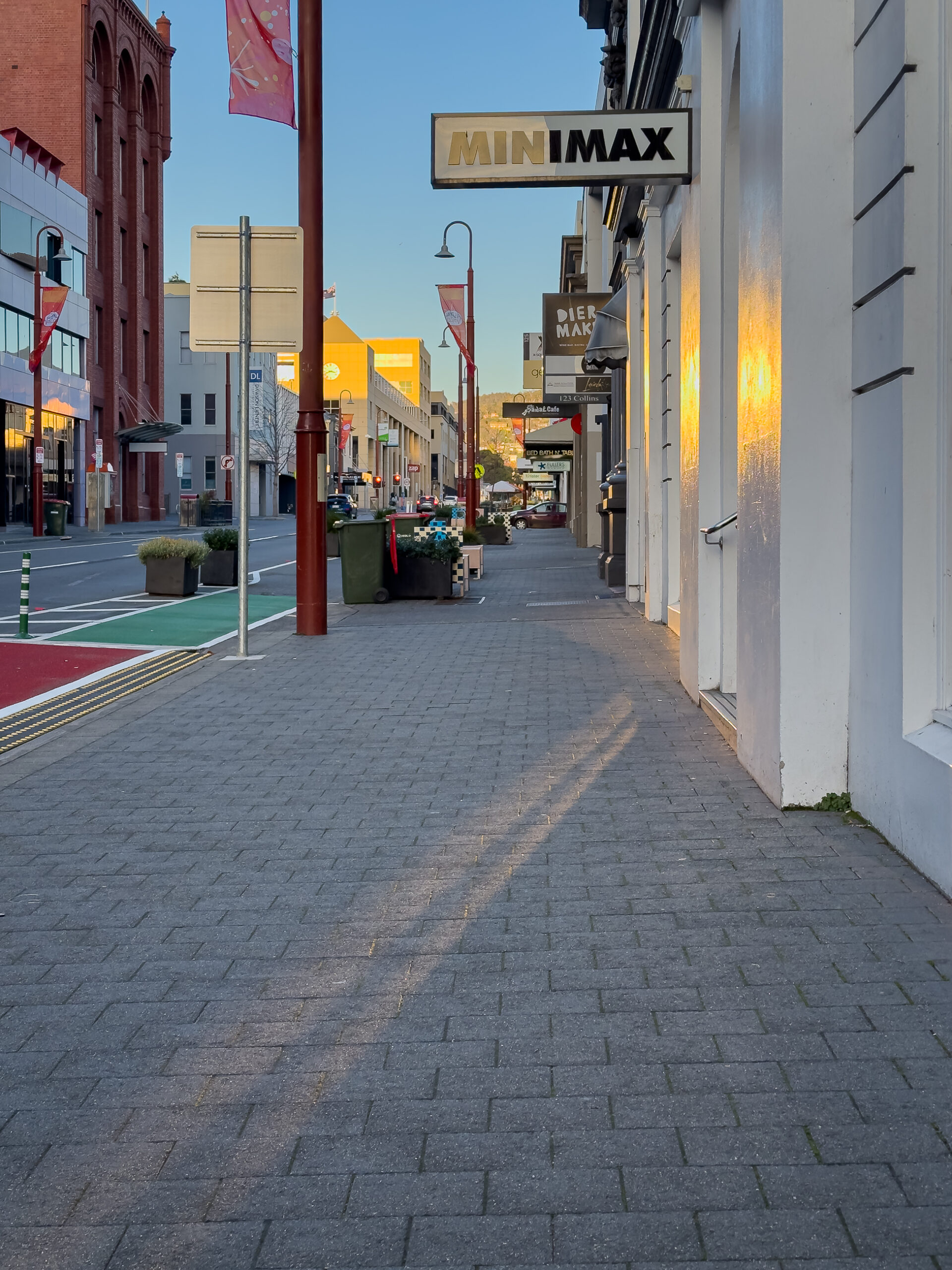 A street view. There is light reflecting onto the facades of the buildings and onto the ground