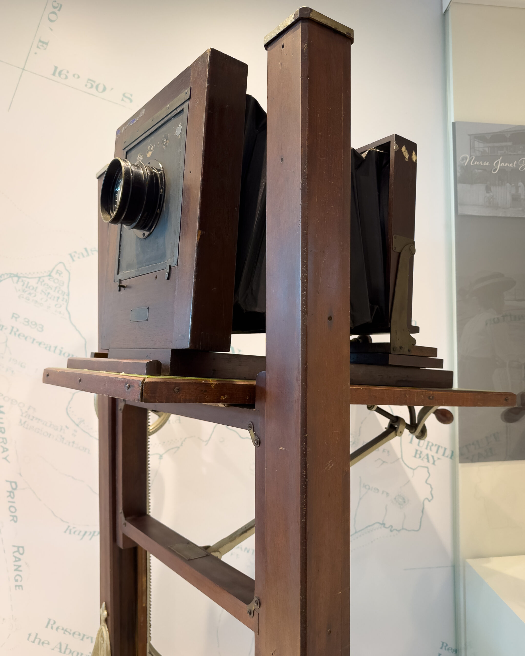 A very old large format camera resting on a wooden stand